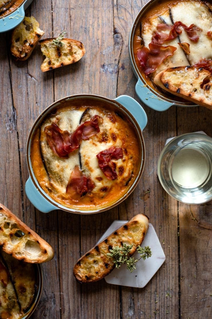 Incredibly delicious Eggplant Lasagna made with layers of eggplant instead of pasta! This low carb lasagna is super comforting made with prosciutto, mozzarella, and a creamy cheese sauce. Perfect comfort food for a rainy day.....or any day for that matter! #lasagna An overhead shot of eggplantt lasagna with grilled ciabatta bread
